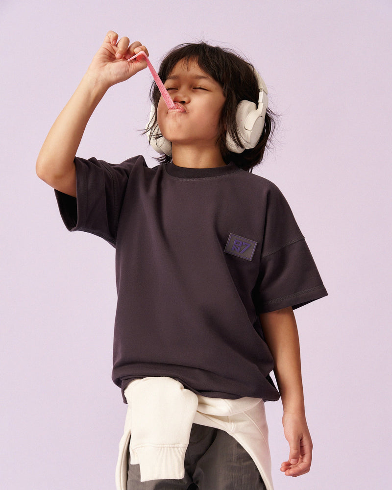 Boy in the ON7 Everyday Tee in graphite with headphones