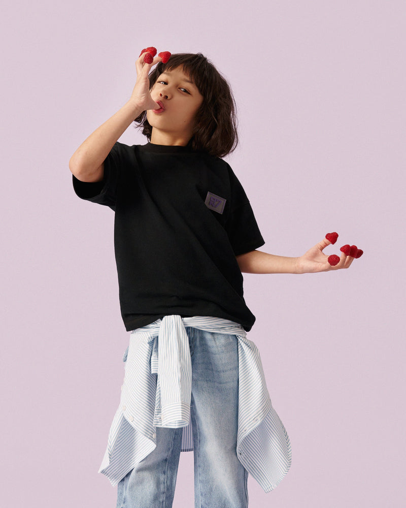 Boy in the ON7 Everyday Tee in black, holding raspberries