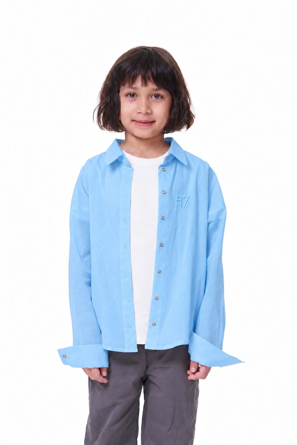 Girl wearing the ON7 Shirt in sky blue, open over a white tee, front view