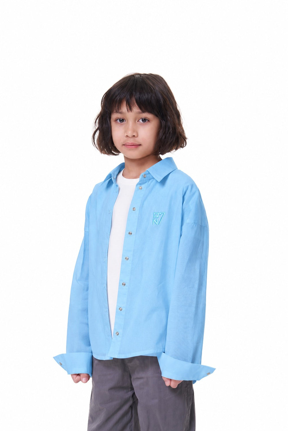 Girl wearing the ON7 Shirt in sky blue, three-quarter view